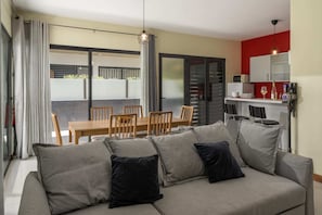 A modern living room with a grey sofa, wooden dining table, and chairs. - Vacation Home in Porto Santo, Villa Girassol (Porto Santo)