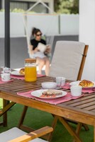 Una mesa de madera con alimentos para el desayuno, como pan, un croissant y un vaso de zumo de naranja.