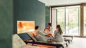 A modern spa room with reclining chairs and a large window offering a view of greenery. - Posthotel Taube (Schruns)
