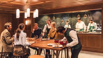 A group of people dining at a restaurant with a wooden interior and hanging pendant lights.