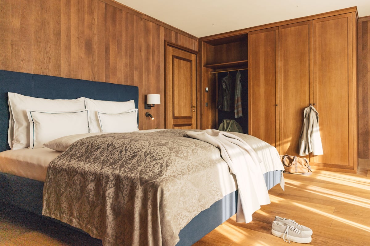 Un dormitorio con una cama grande, un armario de madera y un perchero.