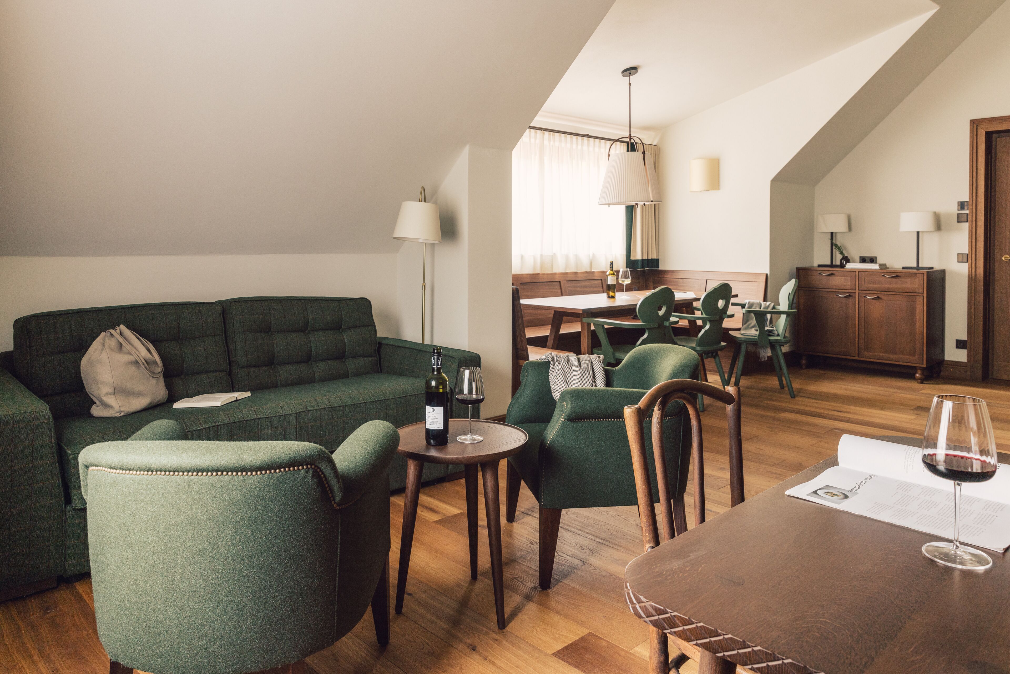 Una sala moderna con un sofá verde, mesa de comedor de madera y sillas a juego.