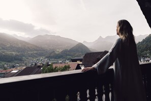 A person standing on a balcony overlooking a mountainous landscape with buildings in the valley below. - Posthotel Taube (Schruns)