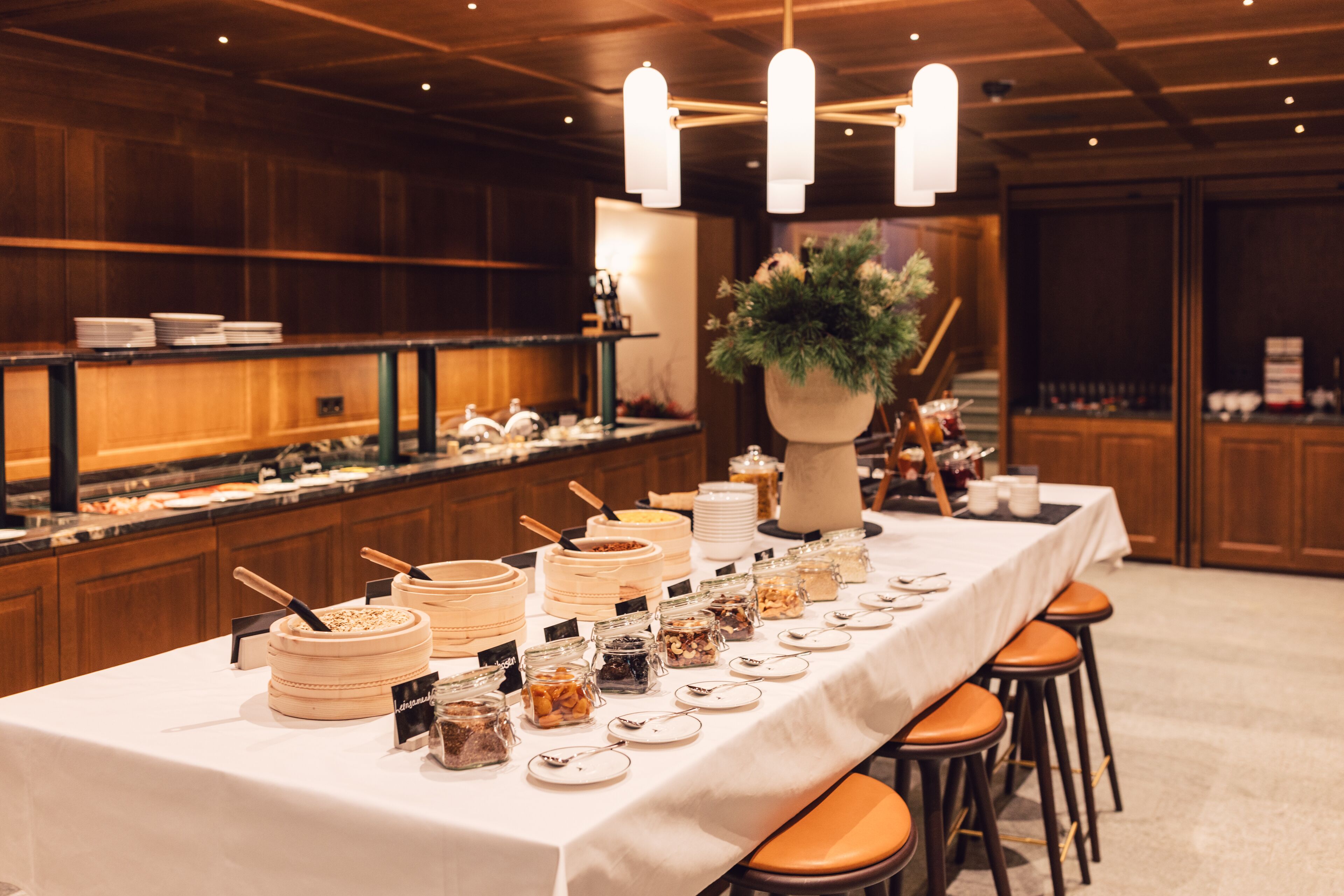 A buffet setup with various food containers and a large vase of flowers.