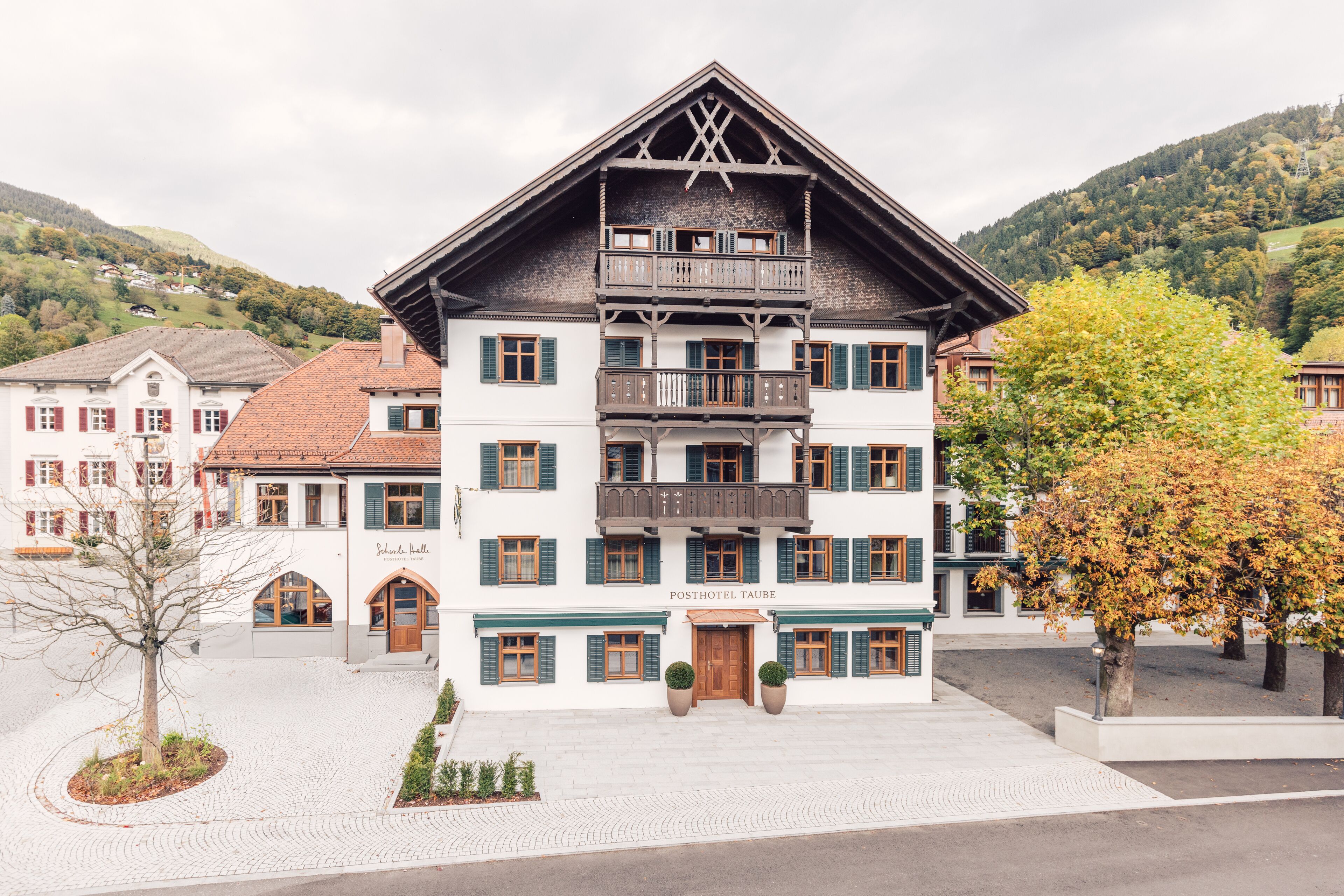 Een traditioneel Europees hotel met een symmetrische gevel, meerdere balkons en een centrale ingang.