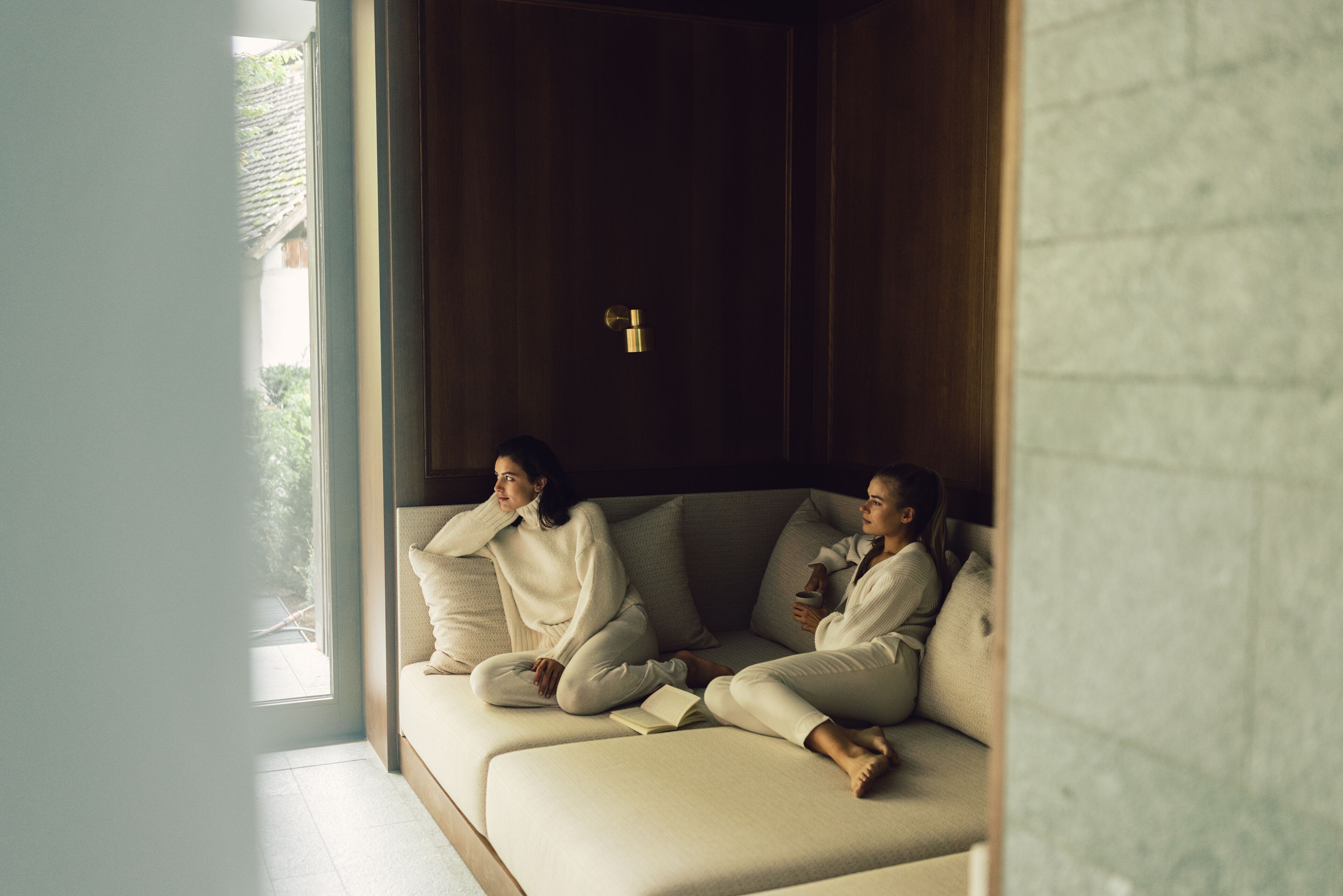 A modern room with a large window, a sofa, and a wooden door.