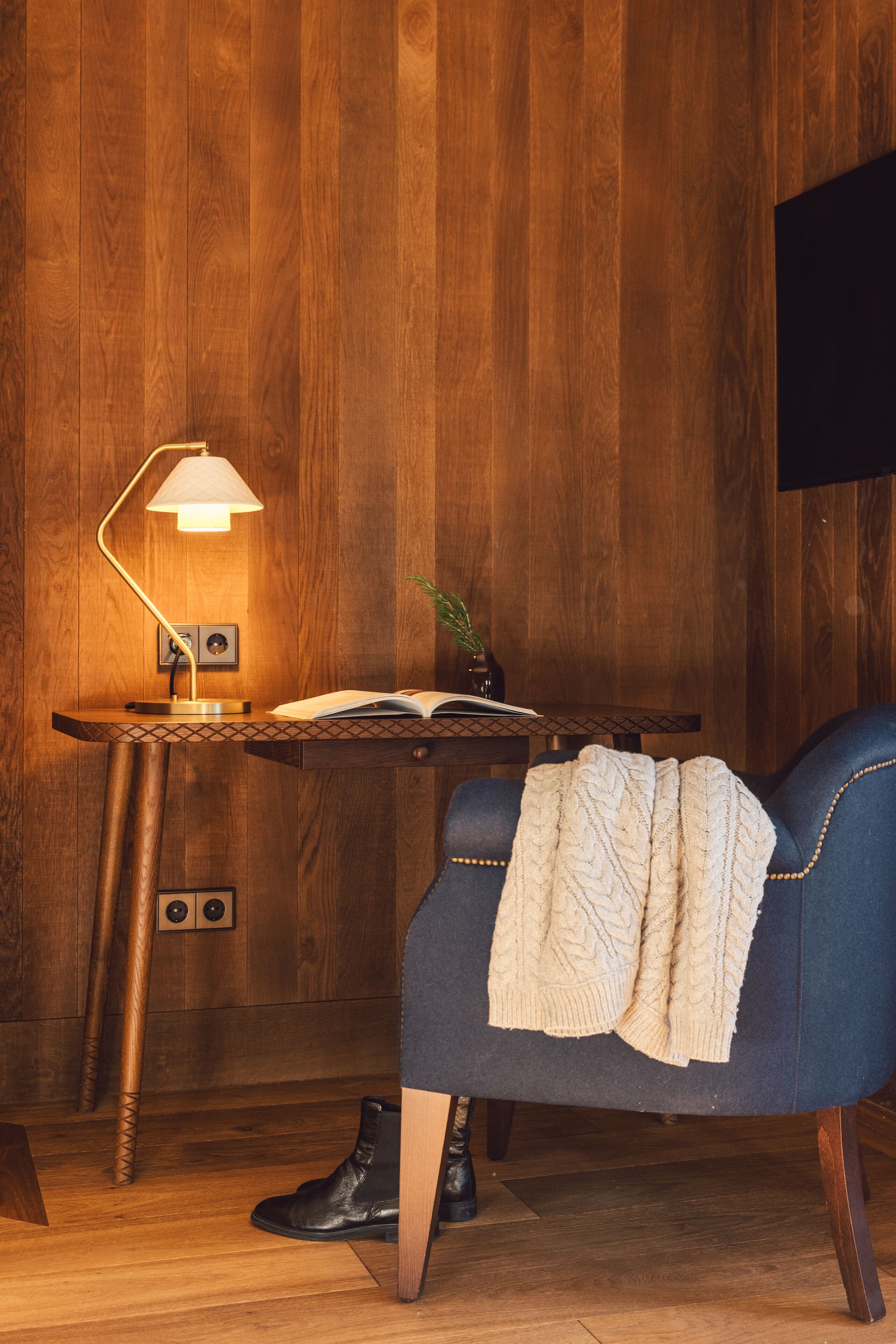 Ein Zimmer mit Holzvertäfelung, einem Schreibtisch, einem Stuhl und einer Lampe.
