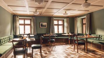 A dining area with green upholstered seating, wooden tables, and chairs.