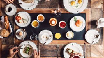 A breakfast setting with various dishes, utensils, and a central candle on a wooden table.