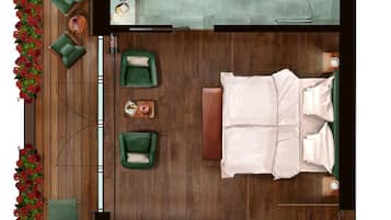 Ein Zimmer mit einem Bett, zwei grünen Sesseln, Holzboden, einem kleinen Tisch mit Lampe und einem Fenster.