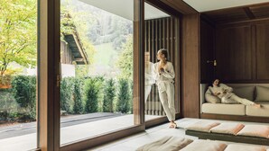 A modern interior with large windows, a wooden wall, and a sofa. - Posthotel Taube (Schruns)