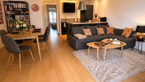 Een moderne woonkamer met een bank, salontafel en eethoek.