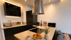 Een moderne keuken met een centraal kookeiland, zwarte kastjes en een roestvrijstalen afzuigkap.