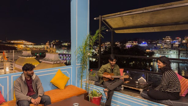 A rooftop terrace with seating, a view of the cityscape, and a decorative fountain. - Madpackers Udaipur (Udaipur)