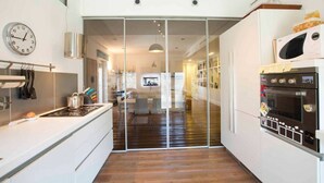 A modern kitchen with a glass door leading to a dining area, a microwave, and an oven. - Entire apartment in Ravda (Ravda, Nessebar community)