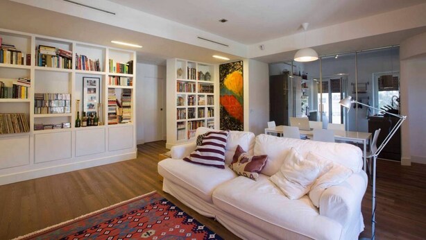 A modern living room with a white sofa, bookshelves, and a large painting. - Entire apartment in Ravda (Ravda, Nessebar community)