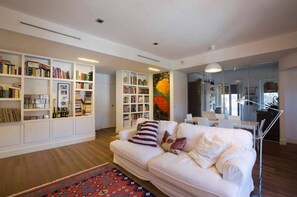 A modern living room with a white sofa, bookshelves, and a large painting. - Entire apartment in Ravda (Ravda, Nessebar community)