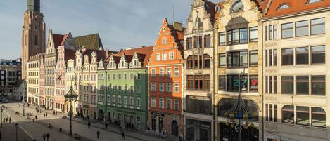 A historic European street with colorful buildings, a prominent church tower, and a tram line.