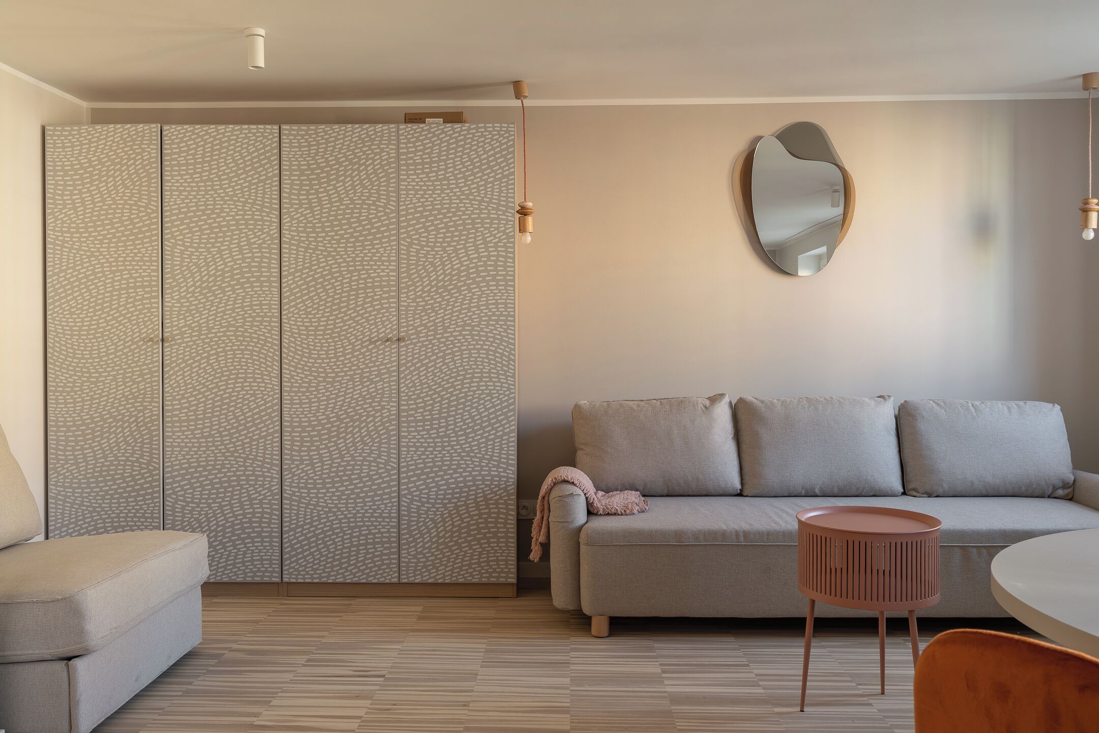 A modern living room with a sofa, a small round table, and a patterned wardrobe.