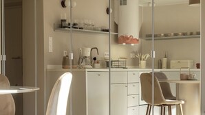A modern kitchen with a glass partition, white cabinets, and a coffee machine.