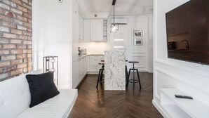 A modern kitchen with white cabinets, a marble island, and bar stools.