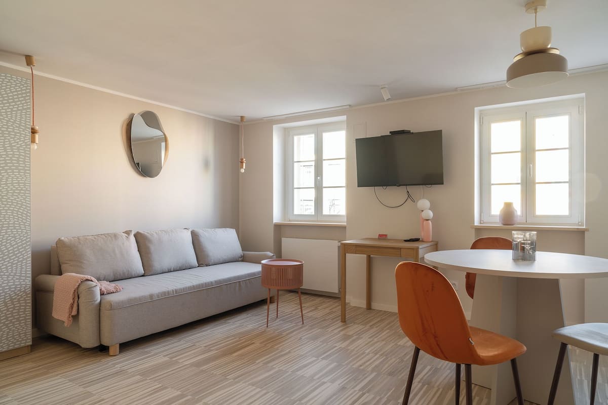 Una sala moderna con un sofá, una mesa redonda y dos sillones naranjas.