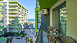 A balcony with wicker chairs and a table, overlooking a parking lot and a building with balconies. - Bianca Residence ALZ (Navodari)