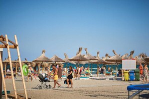 En privat strand, hvidt sand, liggestole, parasoller