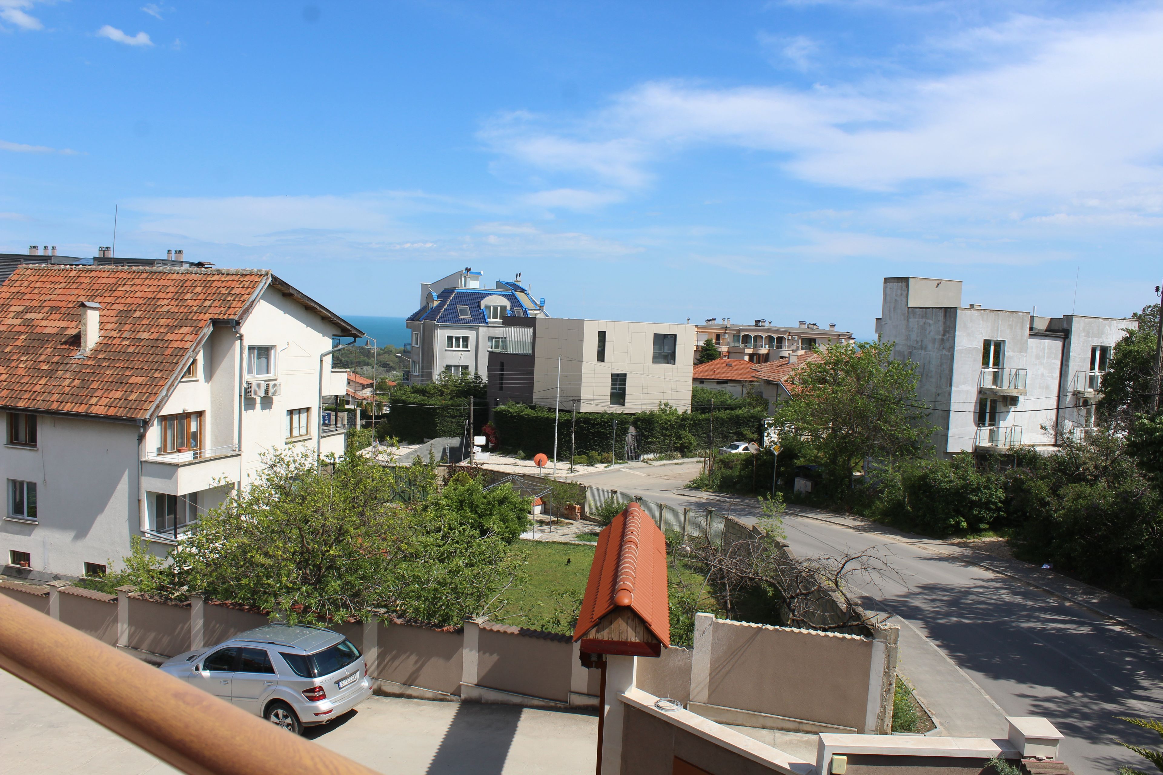 A residential area with houses, a street, and a view of the sea.
