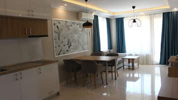 A modern kitchen with white cabinets, a wooden countertop, and a dining area with a table and chairs.