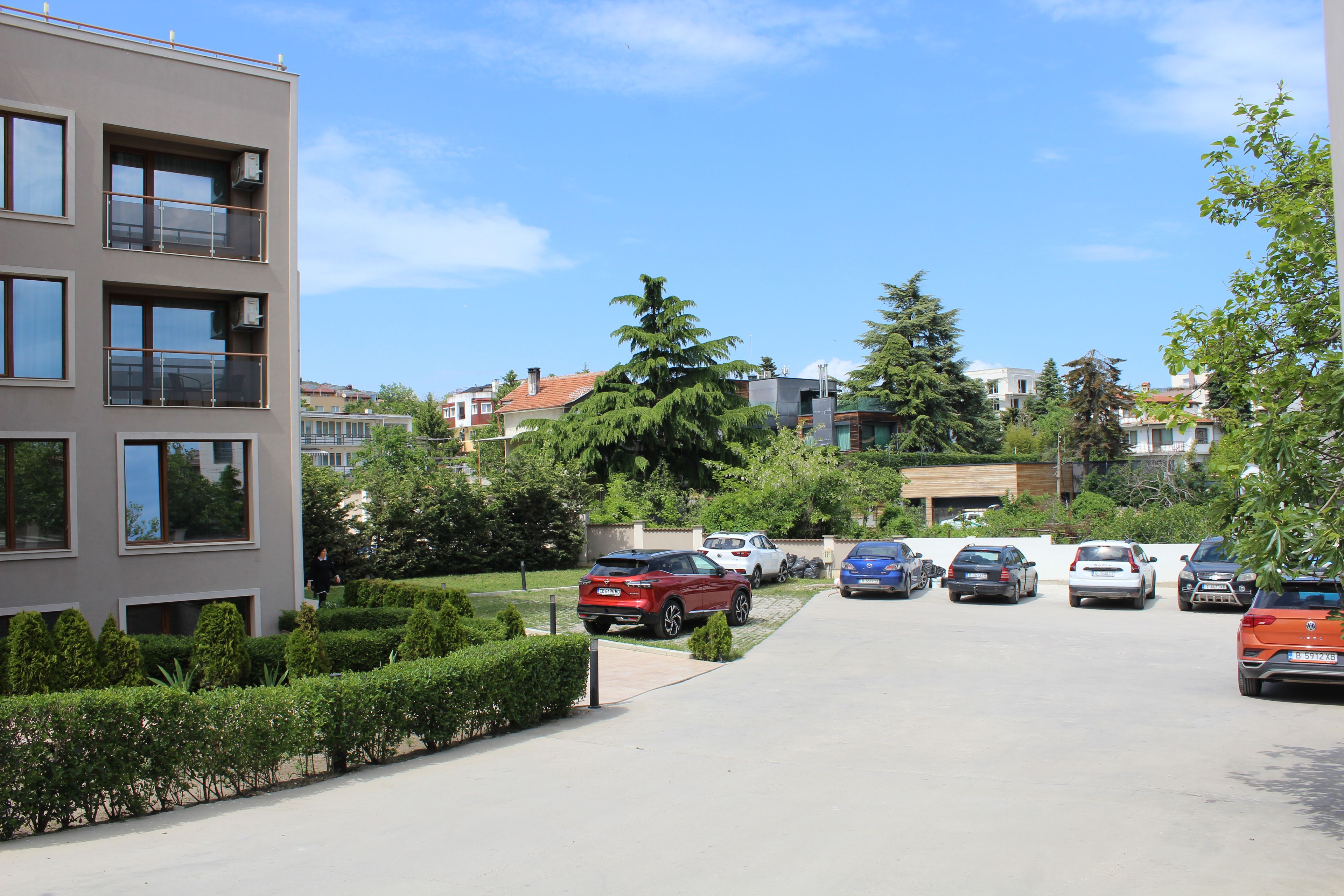 A residential area with modern buildings, a parking lot, and a clear sky.