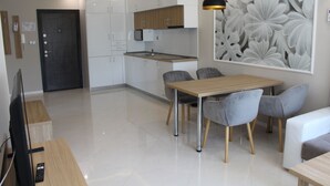 Een moderne keuken met witte kastjes, een houten aanrecht en een zithoek met tafel en stoelen.