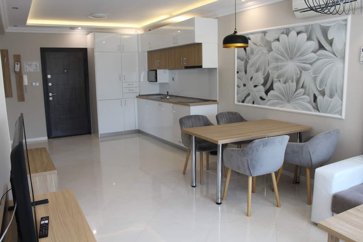 Una cocina moderna con armarios blancos, encimera de madera y comedor con mesa y sillas.