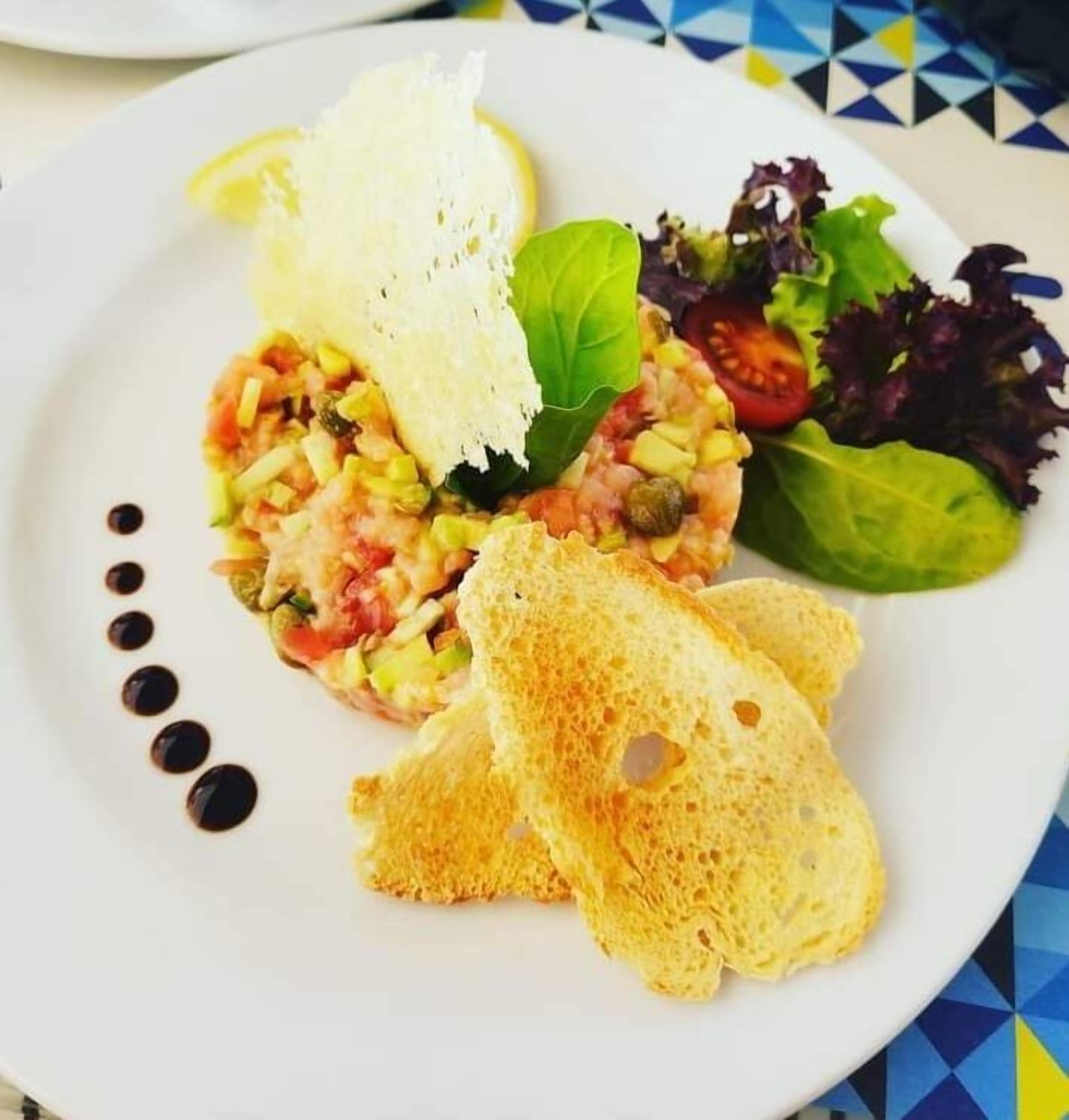 A plate with a seafood dish, bread, and salad.