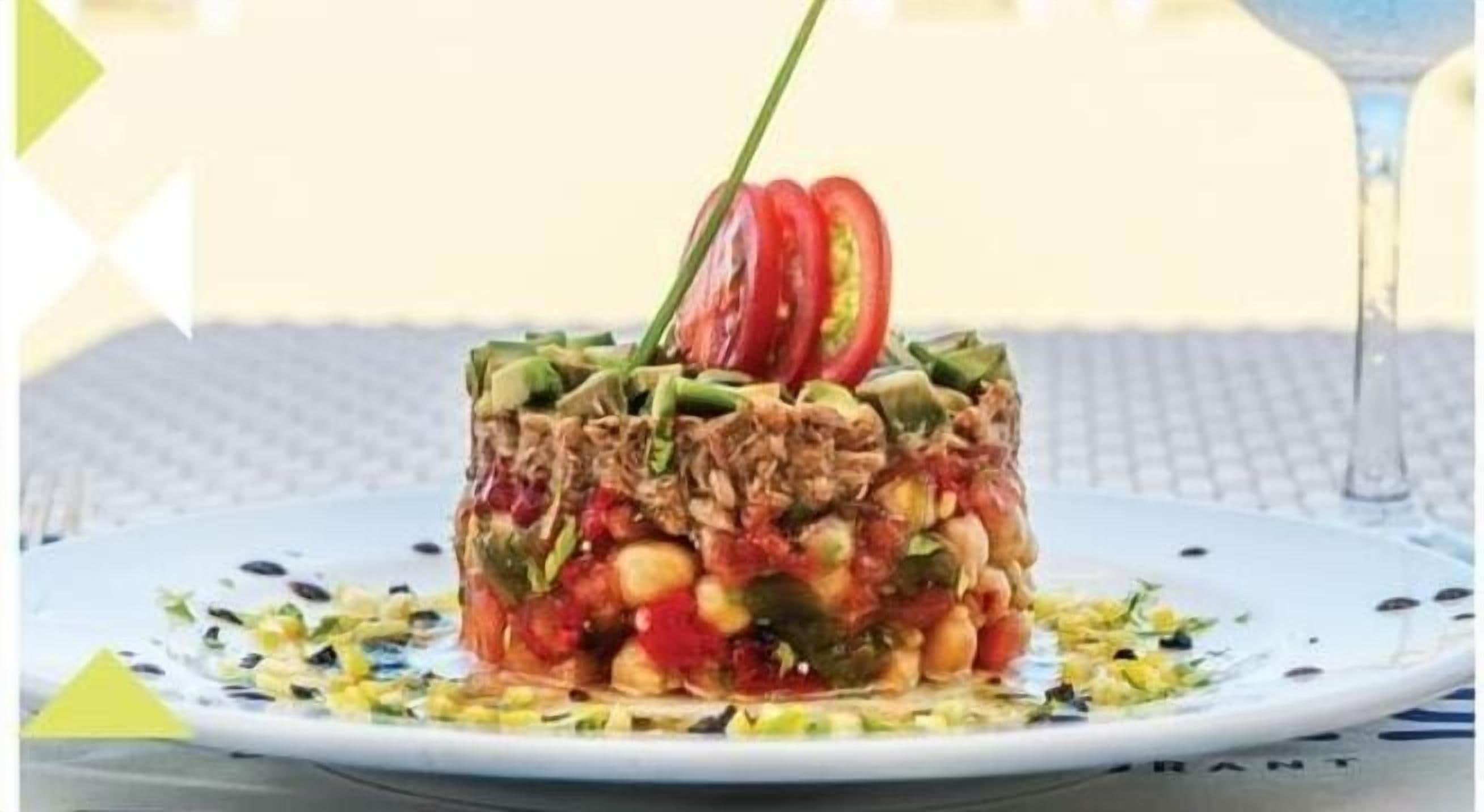 A dish with various ingredients, including tomatoes and green beans, on a white plate.