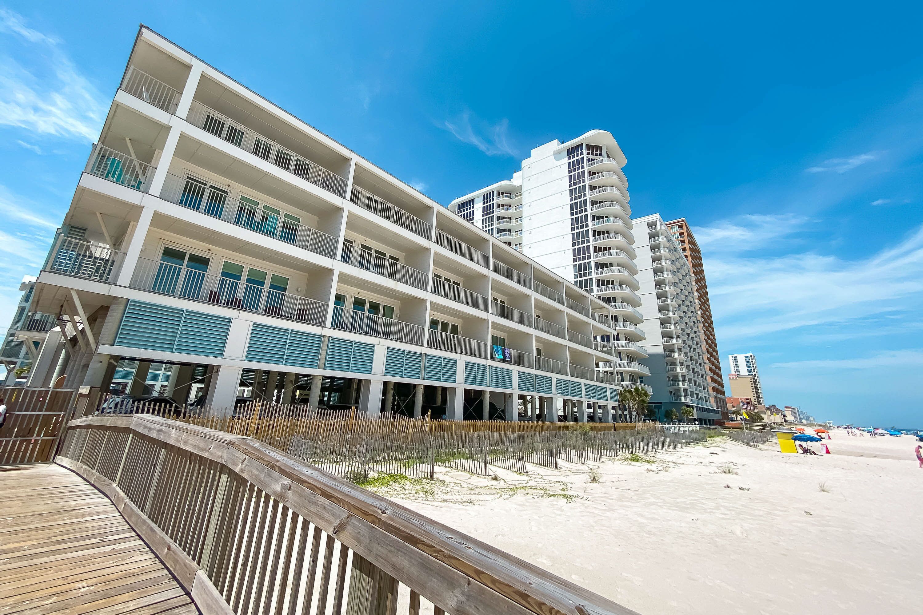 A multi-story hotel with balconies and a beach view.