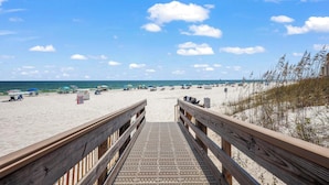 A wooden boardwalk leading to a beach with umbrellas and beach chairs. - HEART OF GULF SHORES, GULF-FRONT BALCONY, POOL! | BEACHBALL PROPERTIES (Gulf Shores)