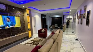 Una sala de estar moderna con un sofá beige grande, un sillón rojo y un televisor de pantalla plana montado en la pared.