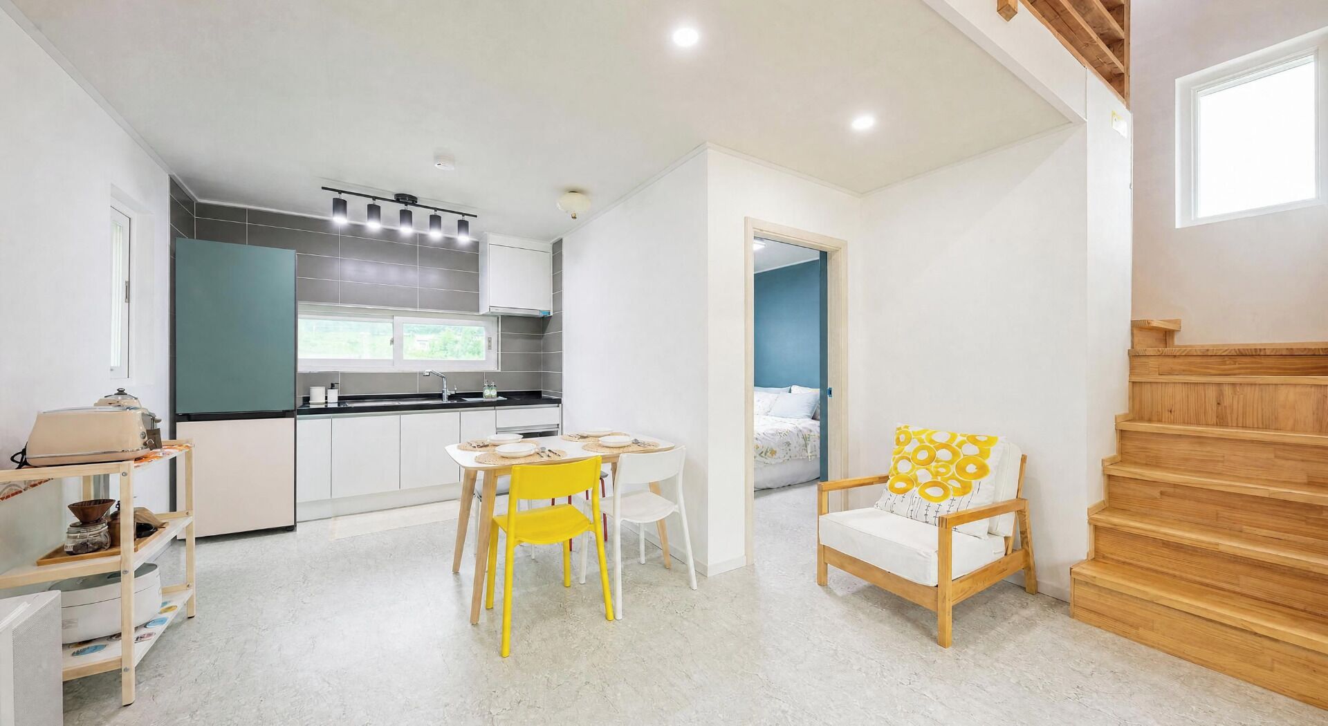 A compact living space with a kitchen, dining area, and a staircase.
