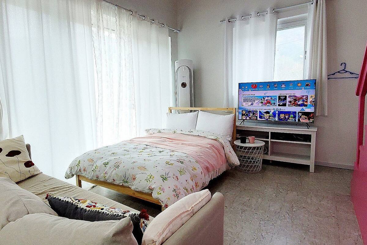A bedroom with a bed, a chair, a TV, and a small table.