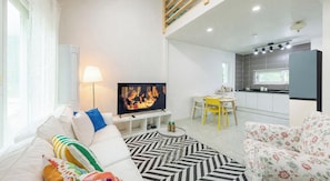A modern living room with a flat-screen TV, a sofa, a dining table with chairs, and a kitchen area with a countertop and cabinets. - Yangyang Jaeins Garden (Yangyang)