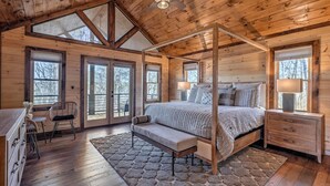 A log cabin bedroom with a four-poster bed, a bench, a desk, and a chair.