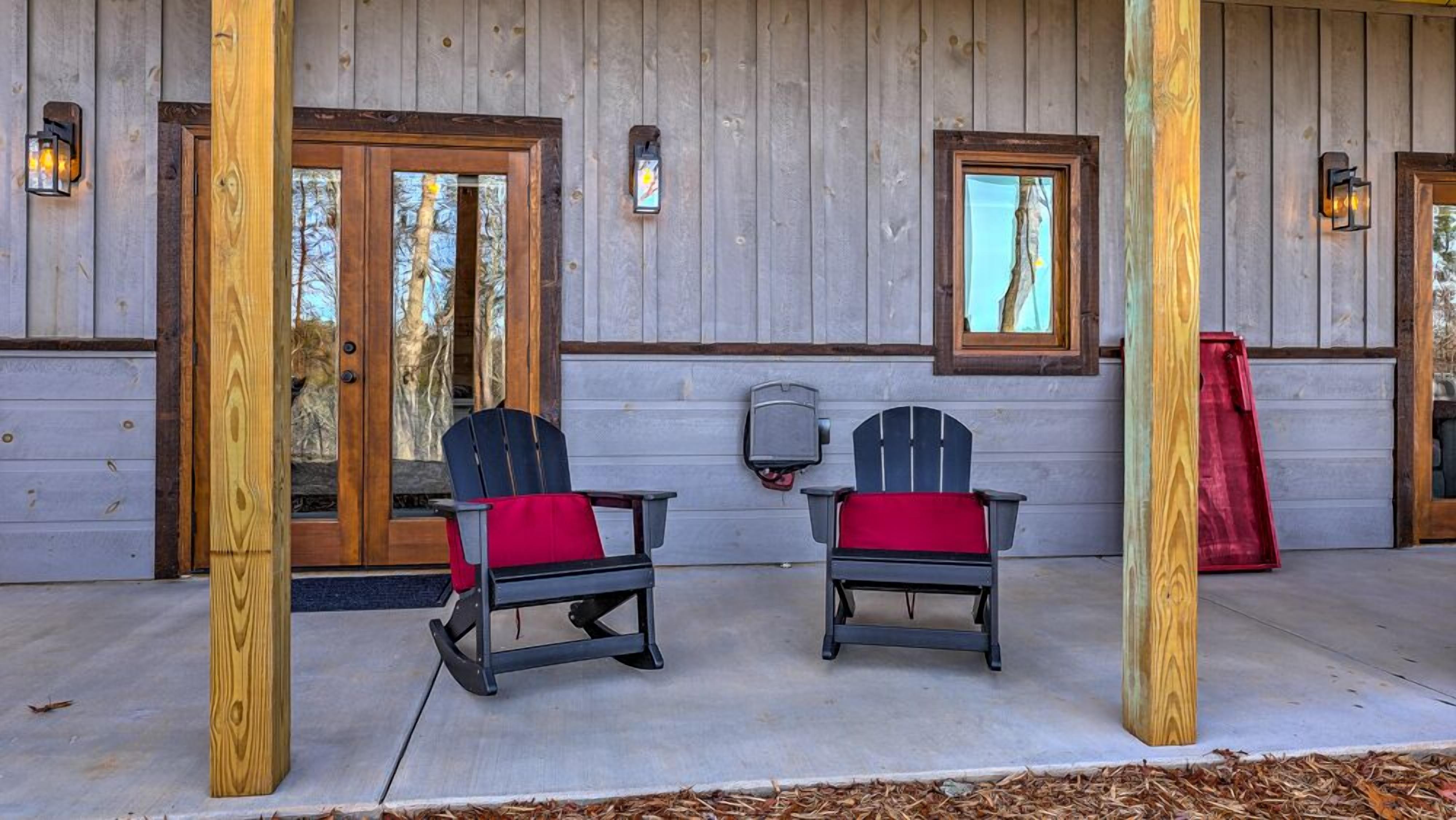 A covered porch with two Adirondack chairs, wooden doors, and a red awning.
