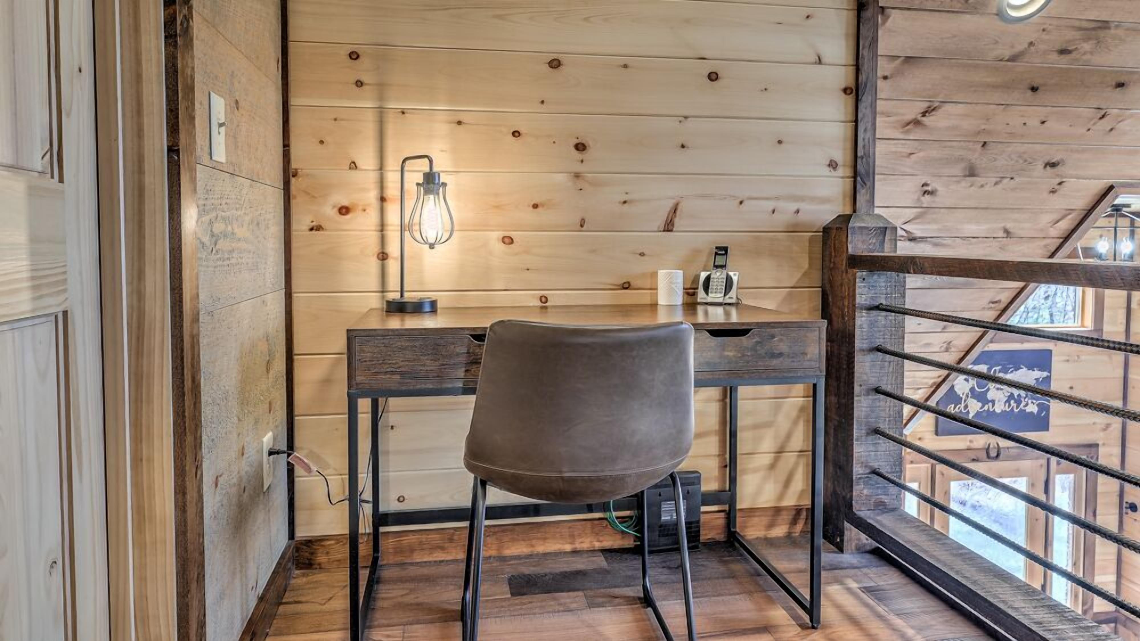 A wooden interior with a desk, chair, and a view through a wooden railing.