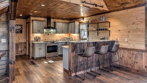 A kitchen with wooden walls, a central island with bar stools, and modern appliances.