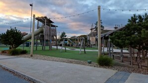 A playground with a slide, climbing structures, and a fenced area. - Memorymakersholiday Sea View (Pwllheli)