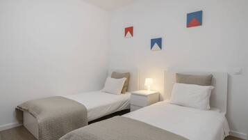 Een slaapkamer met twee eenpersoonsbedden, een nachtkastje met een lamp, en geometrische decoratie aan de muur.
