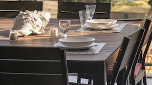 A table set for dining with a view of the ocean and a bridge in the background. - In the Heart of Porto Santo - Casa da Maresia (Porto Santo)