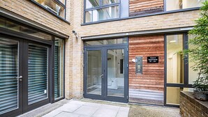 A modern building with a brick facade, large sliding glass doors, and a sign indicating "Core 2 Apartments 37-101". - Comfortable, Modern Flat in Shoreditch (London)