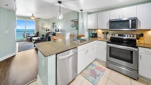 A modern kitchen with stainless steel appliances, a dining area with a view, and a living room with a ceiling fan.